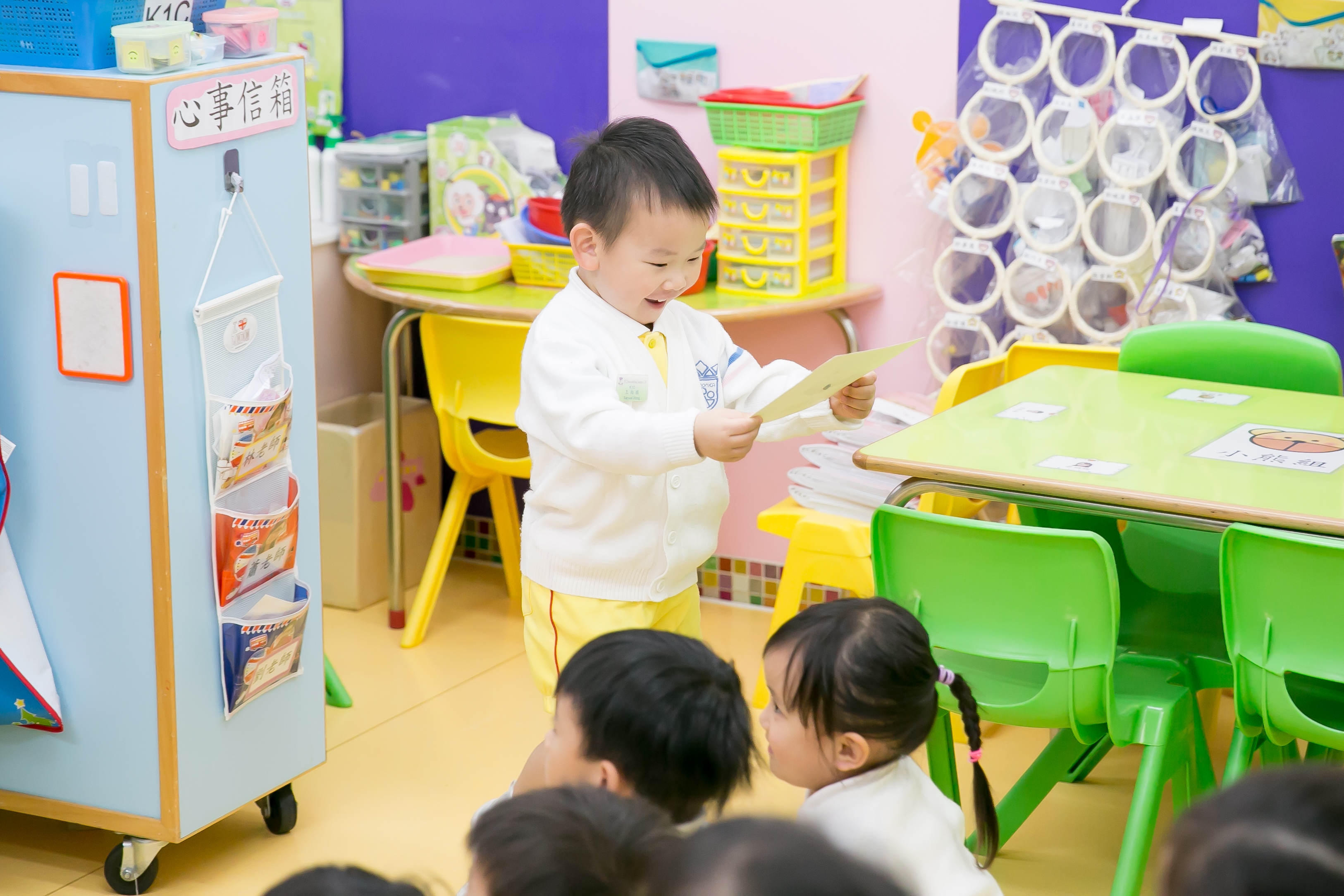 a small asian boy is looking at a picture and smiling