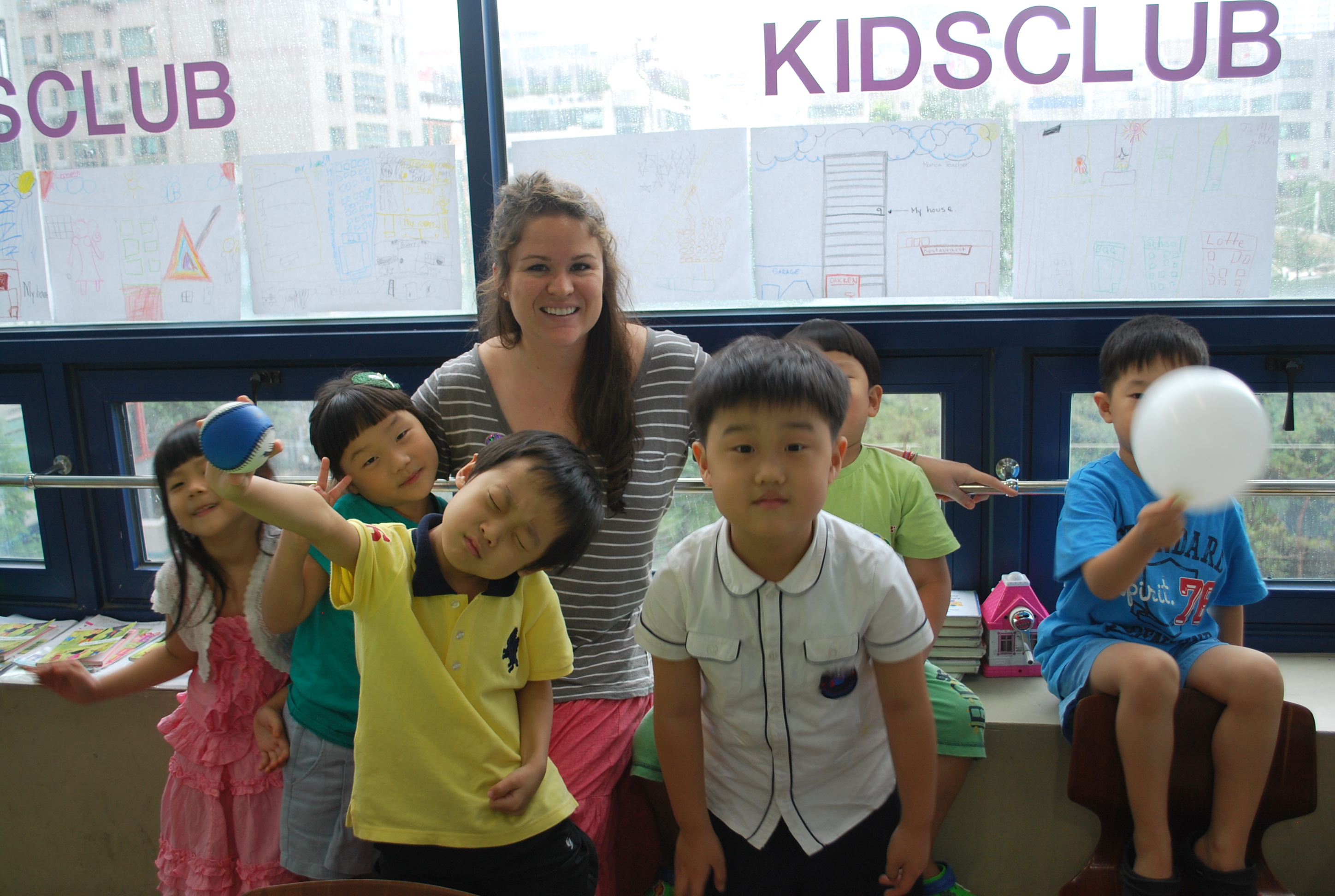 a TEFL teacher with a group of playful asian children in a kidsclub